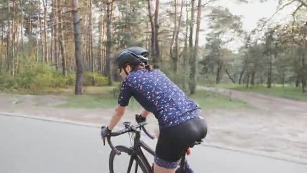 Mujer ciclista montando en bicicleta en el parque. Lado seguir disparo. Formación en ciclismo — Vídeos de Stock