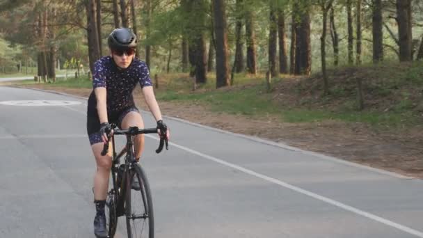 穿着黑色自行车的女孩穿着蓝色球衣和黑色头盔在公园里骑马。自行车比赛训练。慢动作 — 图库视频影像