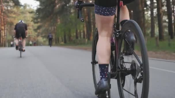 Ragazza che gira pedali su una bicicletta nel parco con ciclisti e corridori sullo sfondo . — Video Stock