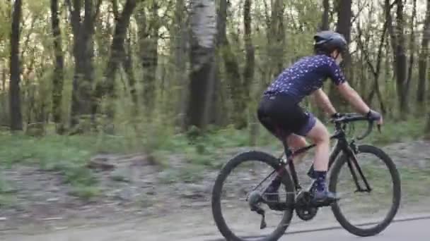 Jonge fitte vrouw op de fiets in het park. Zon door bomen. Volg het schot. Langzame beweging — Stockvideo