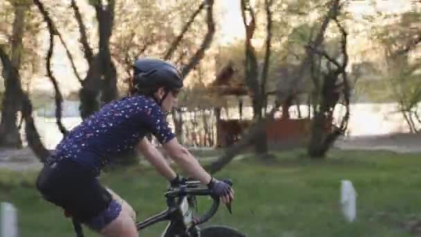 Fit sportieve vrouwelijke fietser op een fiets in het stadspark voor zonsondergang. Cycling concept. — Stockvideo