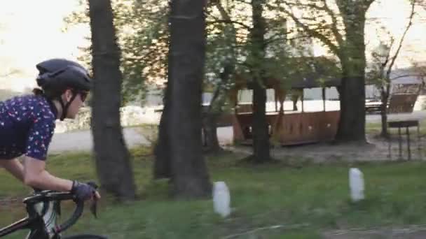 Ajuste enfocado motorista femenino montar fuera de la silla de montar. Siga la vista lateral de la niña entrenando en una bicicleta. Movimiento lento — Vídeo de stock