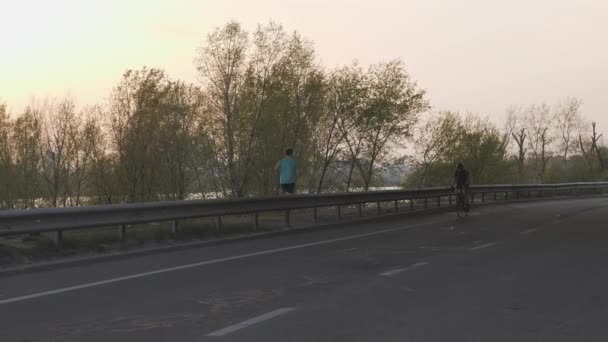 Vrouwelijke fietser rijden naar camera bij zonsondergang. Cinematisch fietsen concept. Slow Motion — Stockvideo