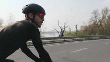 Bisiklette triatlet eğitimi. Yan arka takip atış. Sportif aktif triatlet bisiklete biniyor. Triatlon konsepti. Yavaş çekim
