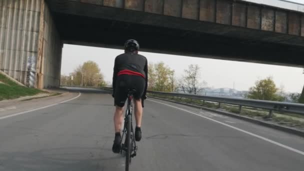 Fit athletic cyclist riding bicycle. Back follow shot. Young bike rider training on bicycle. Cycling concept. Slow motion — Stock Video