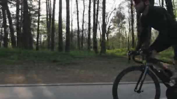 Podle jízdního kola se na kole v parku hodí sebevědomý cyklista. Silné svalstvo nohou otáčející pedály. Cyklistická koncepce. — Stock video