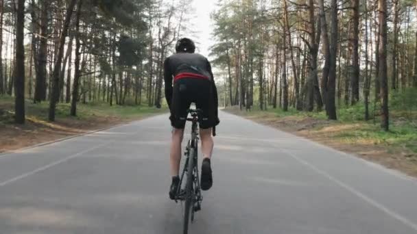 Silný cyklista na kole z sedla. Cyklista se silnými svaly na nohou. Zadní záběr. Cyklistický koncept. Zpomaleně — Stock video