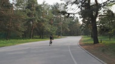 Bisikletçi yarış için eğitim sırasında parkta tek başına sürme. Geri bisikletçi pedal yol bisiklet çekim izleyin. Yavaş çekim