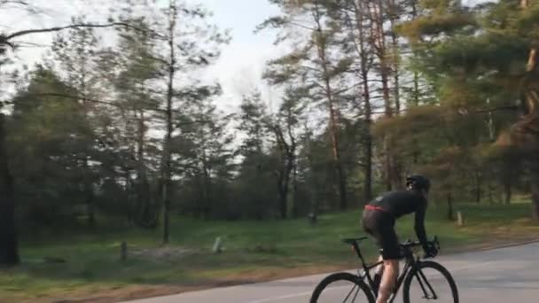 Fit sportieve fietser sprints bergopwaarts uit het zadel. Training op racefiets. Achterzijde Volg schot. Slow Motion — Stockvideo