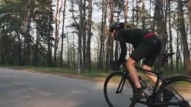 Bike Rider tävlar ur sadeln som en Park av cykling utbildning. Klädd i svart outfit. Starka ben muskler. Slow motion — Stockvideo
