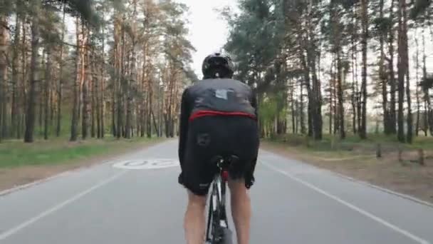 Atrás sigue la foto del ciclista deportivo en forma en traje negro montando bicicleta. Piernas con músculos fuertes pedaleando bicicleta. Concepto ciclista . — Vídeos de Stock