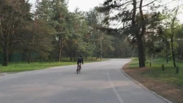 Cyklista jede sám v parku a cvič závodit. Zadní záběr cyklistických silničních jízdních kol. — Stock video