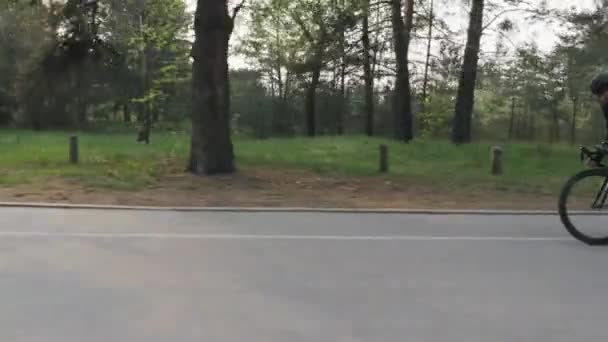 公園でサドルから速く、強いペダリングに自転車に乗ってスキニープロのサイクリストをフィット. — ストック動画