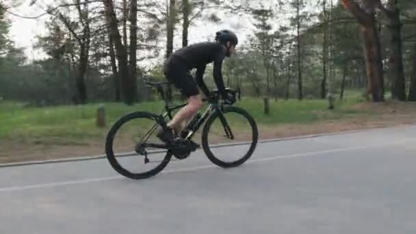 Sterke skinny fit fietser fietsen in het Park. Hoge snelheid fietsen bergopwaarts uit het zadel. Weergave zijkant volgen. Cycling concept. — Stockvideo