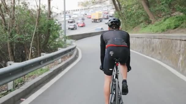 Fietser afdalen naar drukke stad weg het dragen van zwarte sportkleding. Cycling concept. — Stockvideo