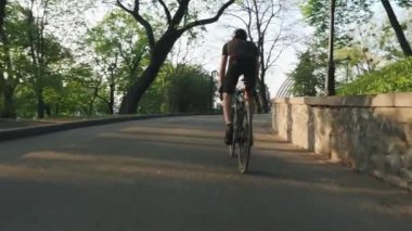 Güçlü profesyonel bisikletçi eyer yokuş yukarı sürmek. Güçlü atletik bacak kasları bisiklet pedal. Yavaş çekim