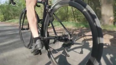 Bisikletle pedal çeviren bisikletçinin güçlü bacak kasları. Bisiklet üzerinde hareket halindeki bisikletçi bacaklarının kamera çekimizleyin. Yavaş çekim
