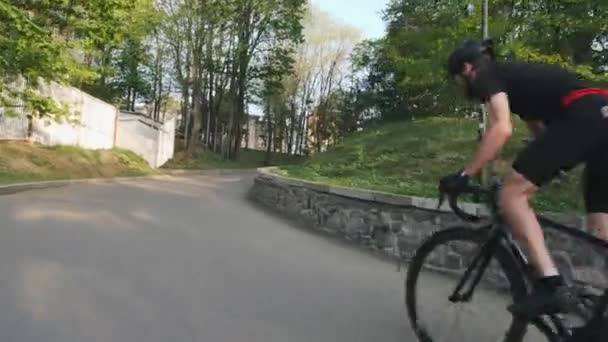 Ciclista con gambe forti che pedala fuori dalla sella arrampicandosi sulla collina. Ciclismo concetto di formazione. Seguire colpo . — Video Stock