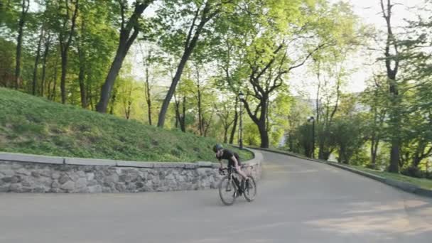 Forte atletico ciclista che corre in salita fuori dalla sella. Bike rider salita collina indossando abbigliamento sportivo nero. Rallentatore — Video Stock