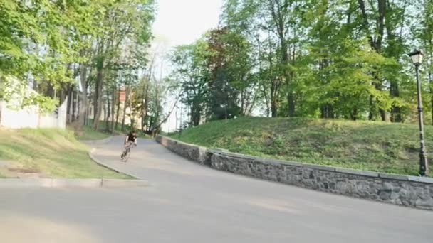 Szakmai erős sovány kerékpár lovas csökkenő a görbe út viselő fekete trikó és rövidnadrág. Kerékpáros megy le a dombra. — Stock videók