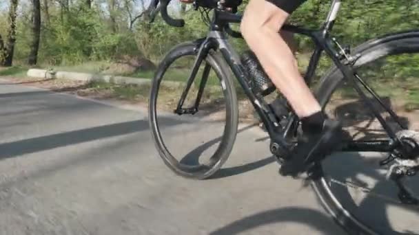 Robuste gambe da ciclista pedalando in bicicletta con ruote a rotazione rapida. Muscoli delle gambe da vicino. Ciclismo concetto di formazione. Rallentatore — Video Stock