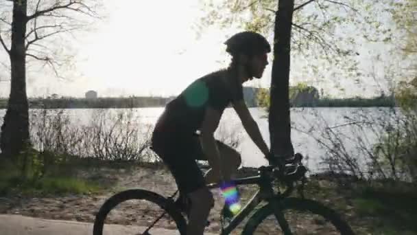 Ciclista profissional beber água de bidon enquanto andar de bicicleta. Rio e cidade em segundo plano. Conceito de ciclismo . — Vídeo de Stock