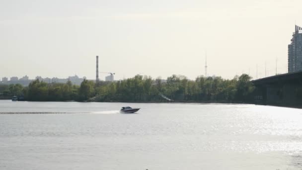 Rápida lancha rápida se mueve rápidamente flotando en el río hacia el puente. Ciudad industrial en el fondo . — Vídeo de stock