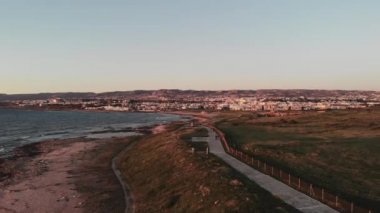 Baf Şehrinin havadan drone görünümü ve yayaların yürüdüğü Akdeniz rıhtımı gün batımı. Rüzgarlı dalgalı deniz ve deniz kıyısı boyunca yol.
