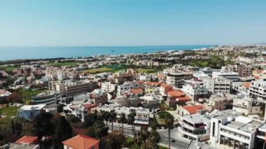 Arka planda binaların çatıları ve okyanus denizi ile Kıbrıs şehir baf üzerinde uçan drone. Havadan çekim