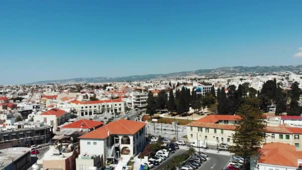 Aerial Pan 360 skott i Paphos stad med bilar, parkeringsplatser och byggnader med röda orange hustak berg i bakgrunden och havet. — Stockvideo