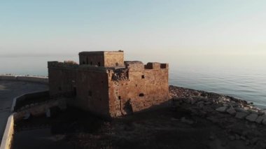 Arka planda deniz ile gün batımı sırasında baf Kıbrıs eski kale drone havadan çekim.