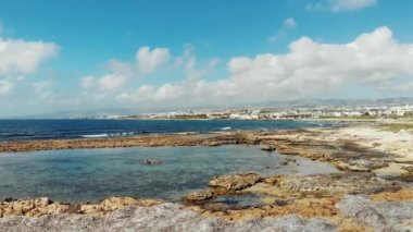 Dalgalı deniz ve sakin koy drone atış. Dağlar ve şehir arka planda. Körfezde berrak okyanus suyu.