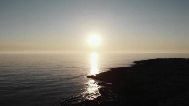 Plano aéreo de sol costa del mar y sol carretera reflexión sobre el agua. Vista del dron del horizonte oceánico antes del atardecer. Playa rocosa en Chipre — Vídeos de Stock