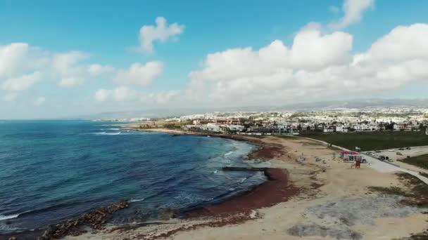 Pandangan udara garis pantai dengan pantai sepi dan pegunungan kota di latar belakang. Gelombang badai yang kuat menghantam pantai berpasir. Pafos Siprus — Stok Video