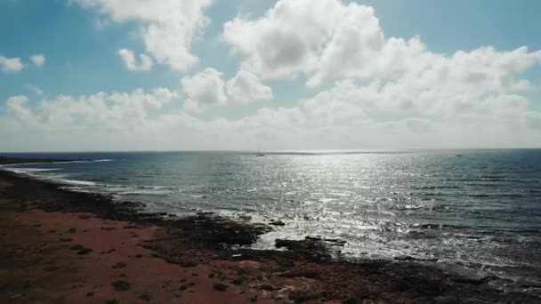 Foto udara dari pantulan sinar matahari di laut yang bergelombang selama matahari terbenam. Gelombang menghantam pantai berbatu. Pantai laut Samudra — Stok Video