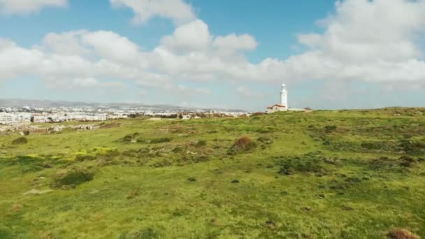 Vue par drone du phare blanc et de la ville en arrière-plan. Paphos Chypre. Ville de montagne et phare et herbe verte. Plan aérien — Video