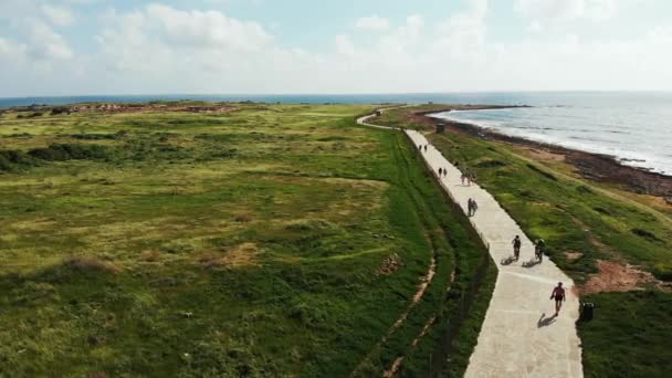 해안 해안선을 따라 걷고 달리는 보행자의 무인 항공기 샷. 바위 해변을 강타하는 강한 파도. 파포스 키프로스 — 비디오