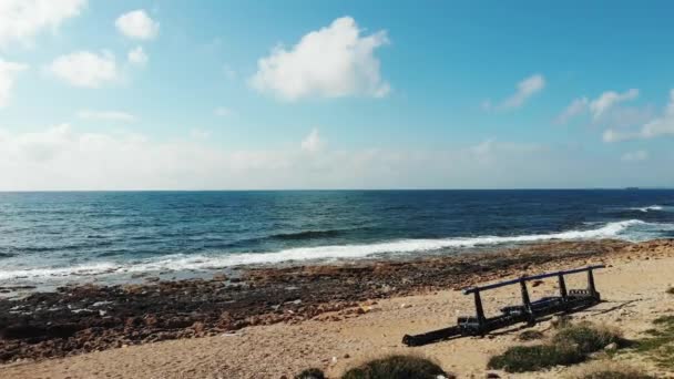 Κηφήνες με κύματα ωκεανών που χτυπούν μολυσμένη βραχώδη αμμώδη παραλία με πλαστικά απορρίμματα και μεταλλικές κατασκευές έμειναν μόνες. Ρύπανση του περιβάλλοντος. — Αρχείο Βίντεο