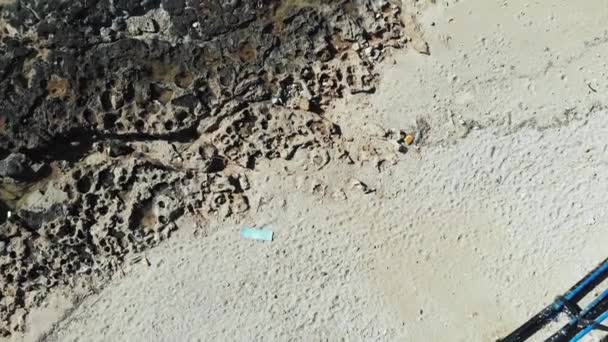 Plastik atık şişeleri ile plaj üzerinde Drone üst görünümü. Kumlu plajda metal inşaat ile kirli kayalık plaj. Plastik atıklar — Stok video