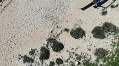 Plastik atık çöp şişeleri ile kumlu plaj üzerinde havadan üst atış. Plastik şişe ve çöp yığını ile Kirli kumlu kayalık plaj.