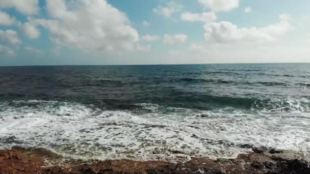 Drone shot van oceaan golven die rotsachtige strand raken. Luchtfoto van zee golven spetteren tegen het strand — Stockvideo