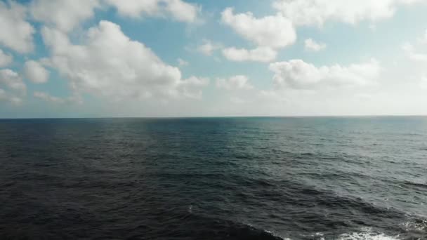 Vue aérienne de l'horizon océanique avec ciel bleu et nuages. Vagues fortes frappant plage rocheuse créant de la mousse et éclaboussures 