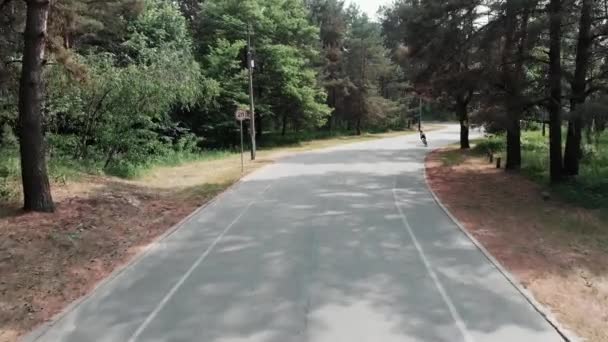 Die junge sportliche Triathletin beginnt, mit dem Fahrrad auf einem Radweg zu fahren. Drohnenblick von vorn — Stockvideo