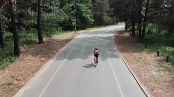 Attraktive junge Mädchen in einem rosa Trikot und einer schwarzen Shorts entspannt und genießt ihre Fahrt draußen im Park. Radverkehrskonzept — Stockvideo