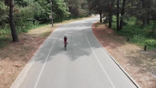 Fiduciosa ragazza in forma focalizzata sta andando in bicicletta indossando un vestito rosa e casco nero. Concetto di triathlon . — Video Stock