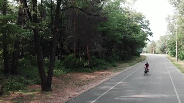 Sportive jonge fietser meisje in roze pak bijna valt van haar fiets op het fietspad in het Park. Cycling concept — Stockvideo