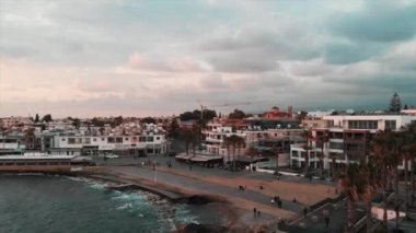 İskele ve kafeler ile şehirde turistik alanda Drone çekim. İskelenin yakınında yürüyen ve fotoğraf çeken turistler. Dağ manzarası ile şehrin havadan drone görünümü.