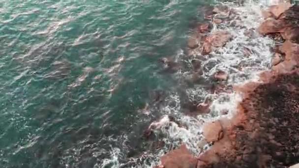 Vzdušný pohled na mořské vlny dopadajícího na skály. Pohled zblízka na skalnaté pobřeží s velkými vlnami za větrného dne. — Stock video
