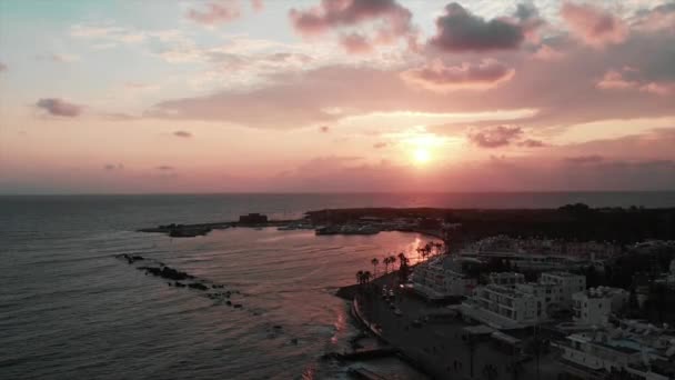 Luchtfoto van actieve toeristische gebied met palmen, auto's, bars en hotels bij de zonsondergang. Drone uitzicht op de haven van de stad bij de zonsondergang. — Stockvideo