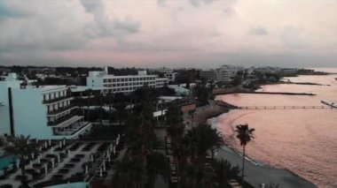 Drone gün batımında oteller ve palmiye ile turistik alanın yakınında uçar